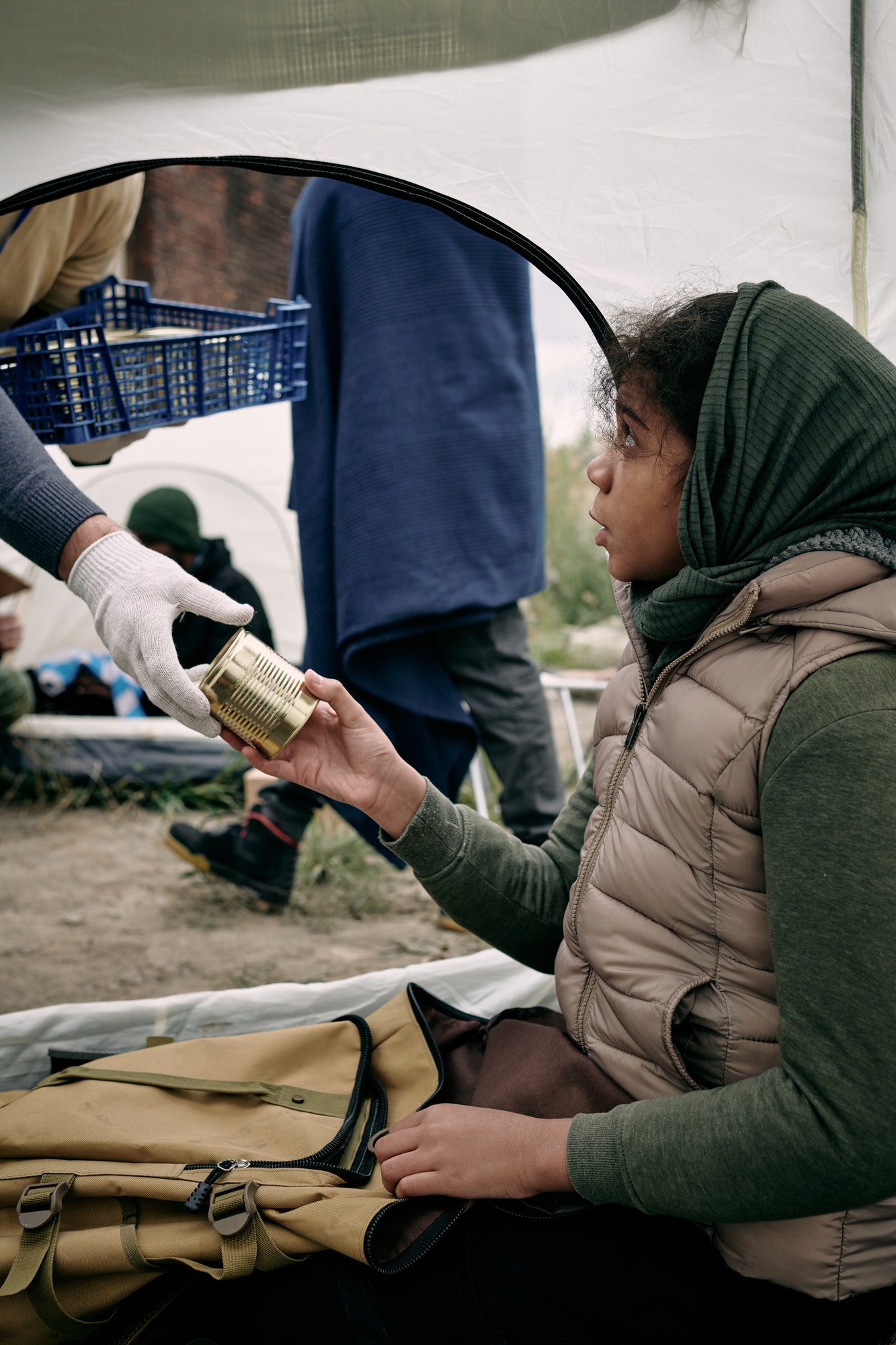 hungry-girl-refugee-taking-tinned-food-from-gloved-hand-of-volunteer